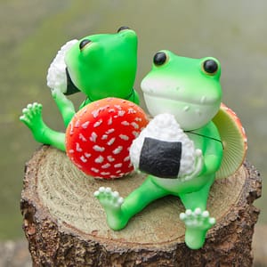 ベニテングタケ帽を背に日本産の米でできたおにぎりを感謝して食べるカエル